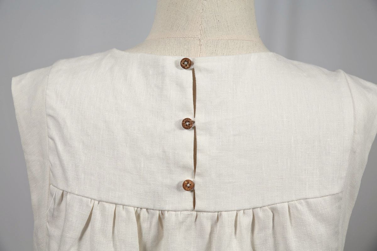 Back of a linen dress with three coconut buttons